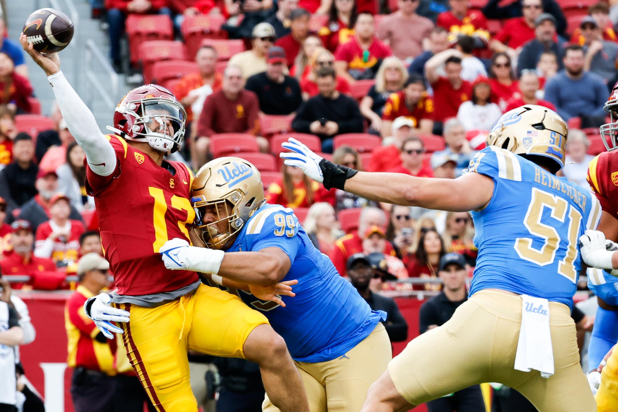 USC quarterback Caleb Williams throws a pass while getting tackled by UCLA defensive lineman Keanu Williams Saturday.