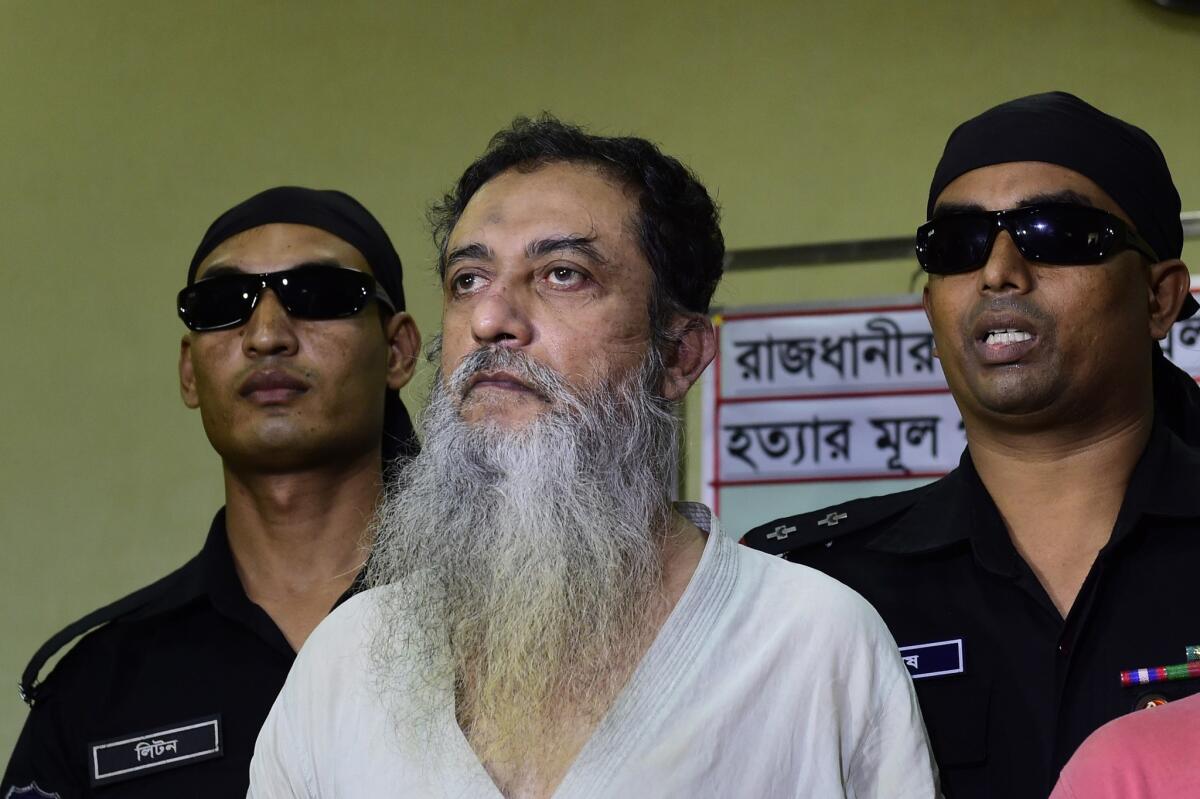 Bangladeshi Rapid Action Battalion personnel in black accompany Touhidur Rahman in Dhaka on Aug. 18. Rahman was arrested along with two other suspects in the slayings of two prominent atheist bloggers.