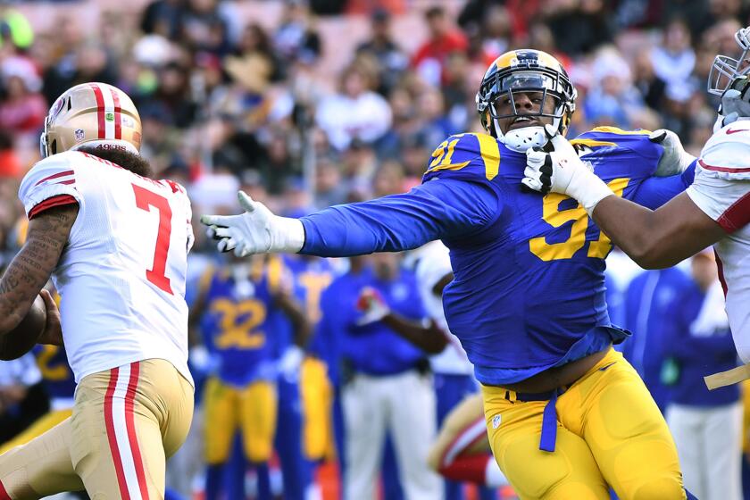 Rams defensive lineman Dominique Easley is held by 49ers Joshua Garnett for a penalty as Colin Kaepernick runs by in the first quarter at the Coliseum.