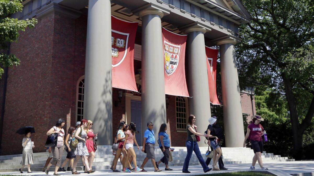 A tour group walks past a columned building on the Harvard campus in 2012.