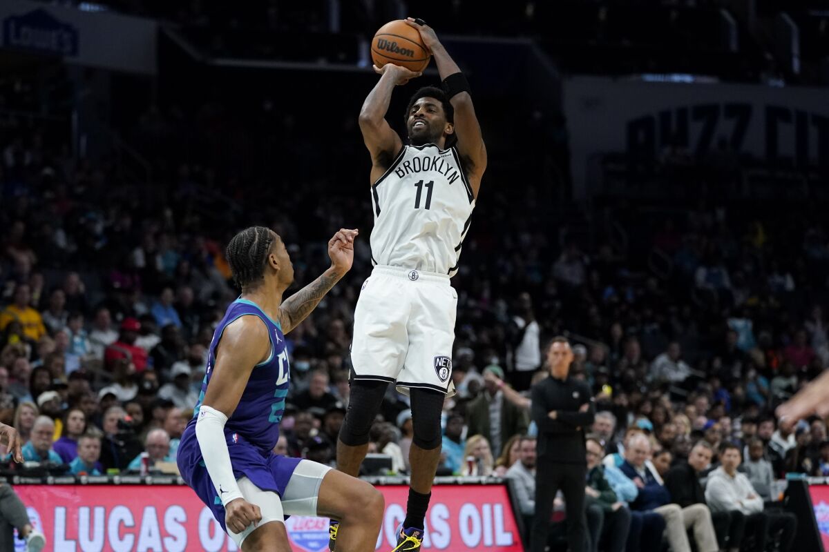 Brooklyn Nets guard Kyrie Irving scores over Charlotte Hornets forward P.J. Washington during the second half of an NBA basketball game on Tuesday, March 8, 2022, in Charlotte, N.C. (AP Photo/Chris Carlson)