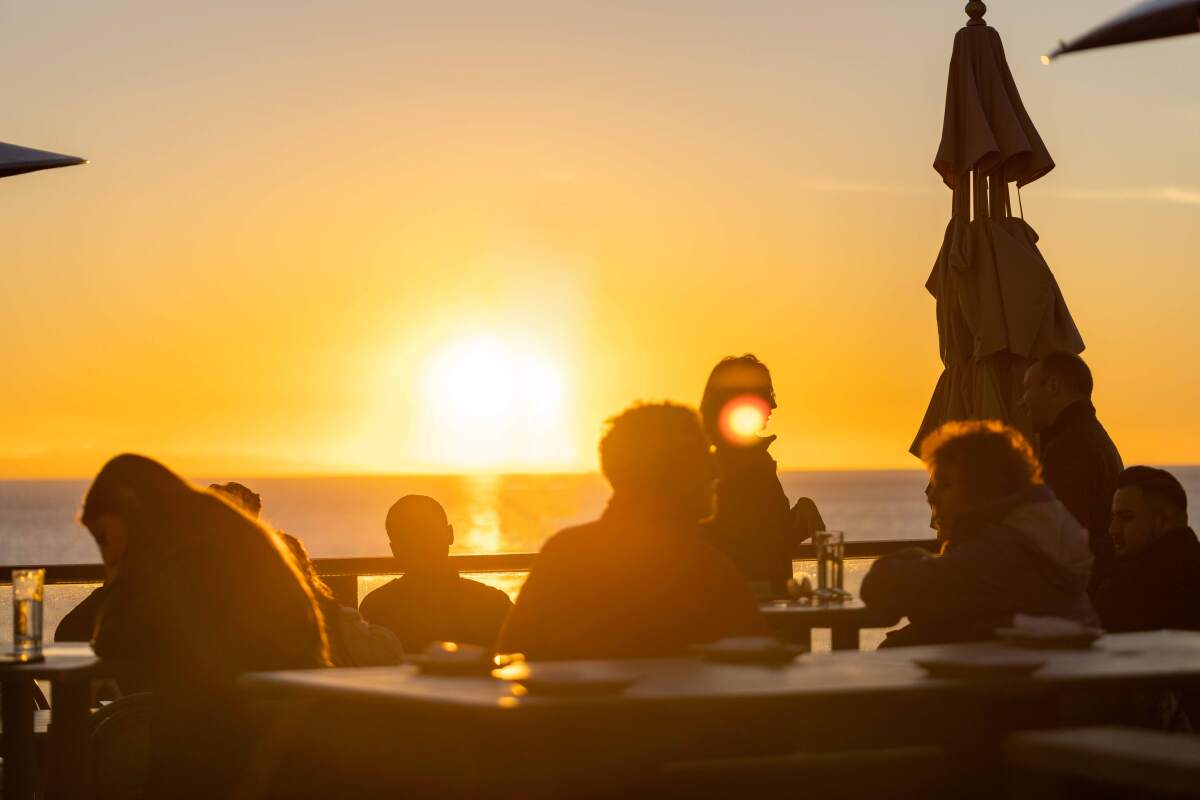 People seated at the Rooftop Lounge in Laguna Beach as the sun sets behind them