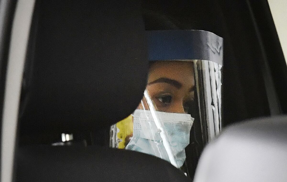 Sarah Caisip wears a protective mask after viewing her father's body at a funeral home in Brisbane, Thursday, Sept. 10, 2020. Caisip was refused permission to go to her father Bernard Prendergast's funeral because she was forced to spend 14 days in a hotel quarantine. (Darren England/AAP Image via AP)