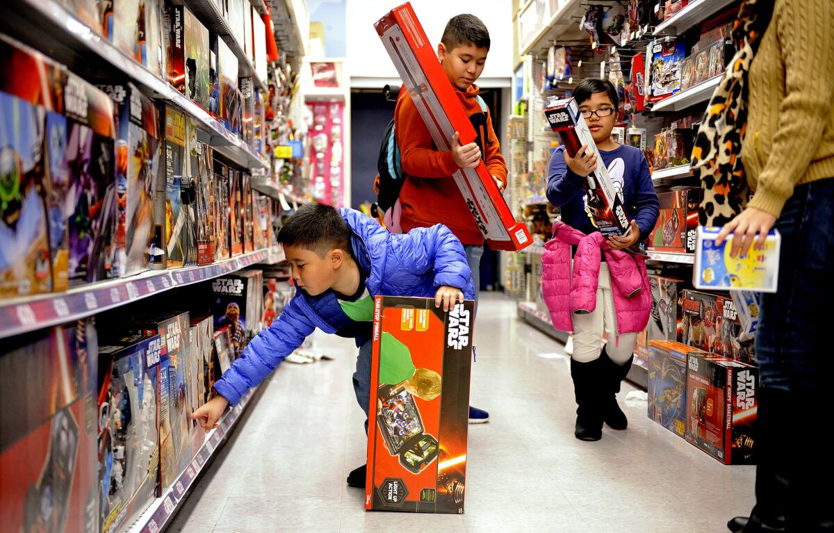 From left, Inaki, 7, Inigo, 13, and Bianca Casido, 9, shop at a Toys R Us store in Los Angeles with their mother Kristine, right, on Dec.14, 2015.