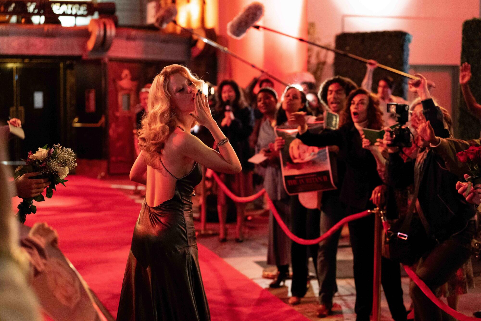 A glamorous woman walks the red carpet at her movie's premiere.