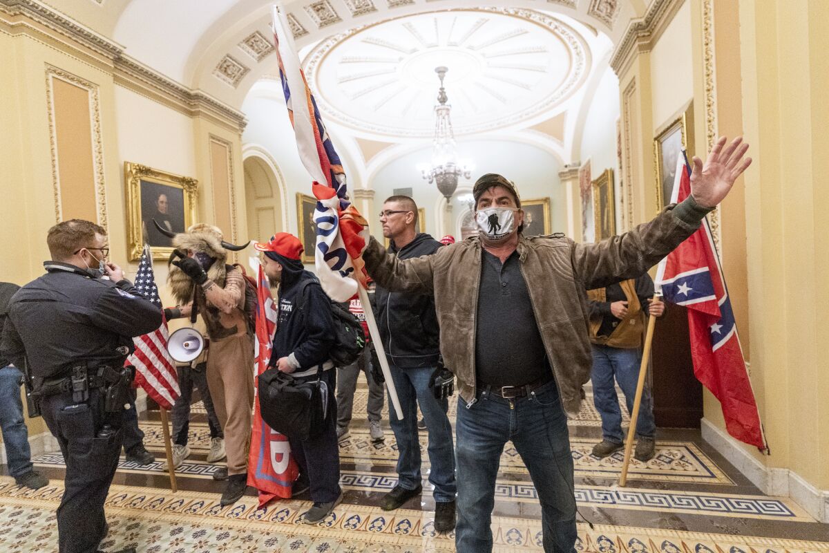 Trump supporters, some carrying Confederate symbols, confront U.S. Capitol Police officers during the Capitol invasion.