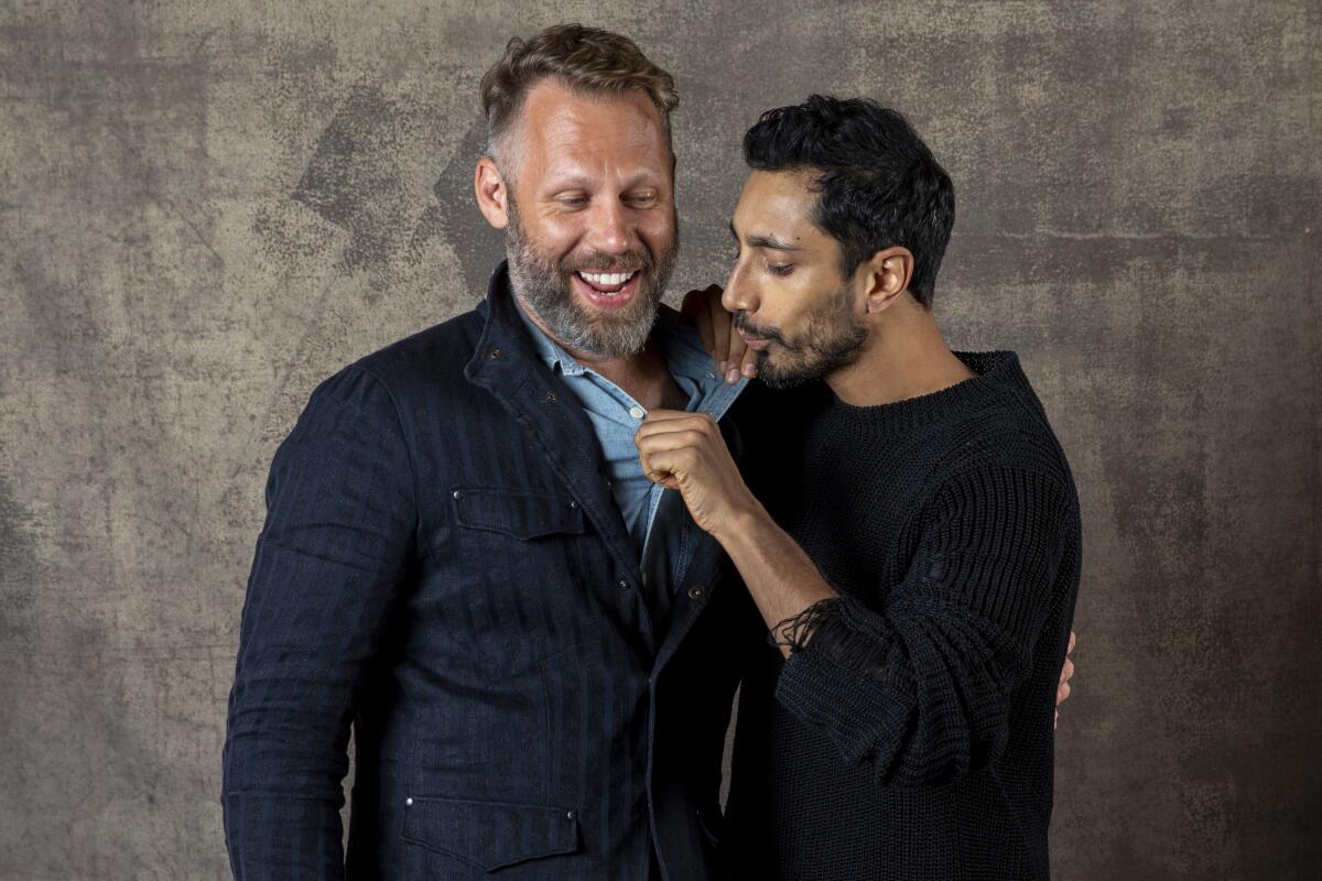 Riz Ahmed blows into the shirt of "Sound of Metal" filmmaker Darius Marder.