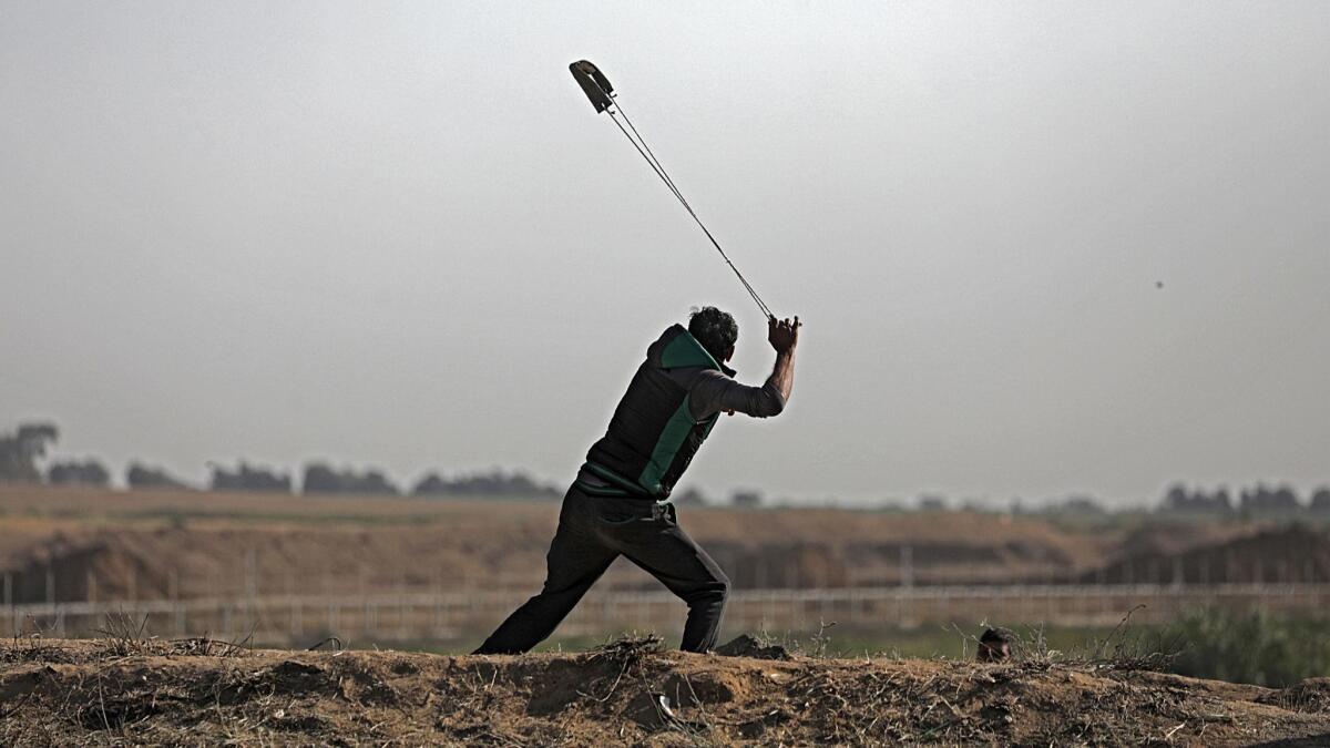 A Palestinian protester hurls stones during clashes with Israeli troops along the border between Israel and the Gaza Strip on March 31.