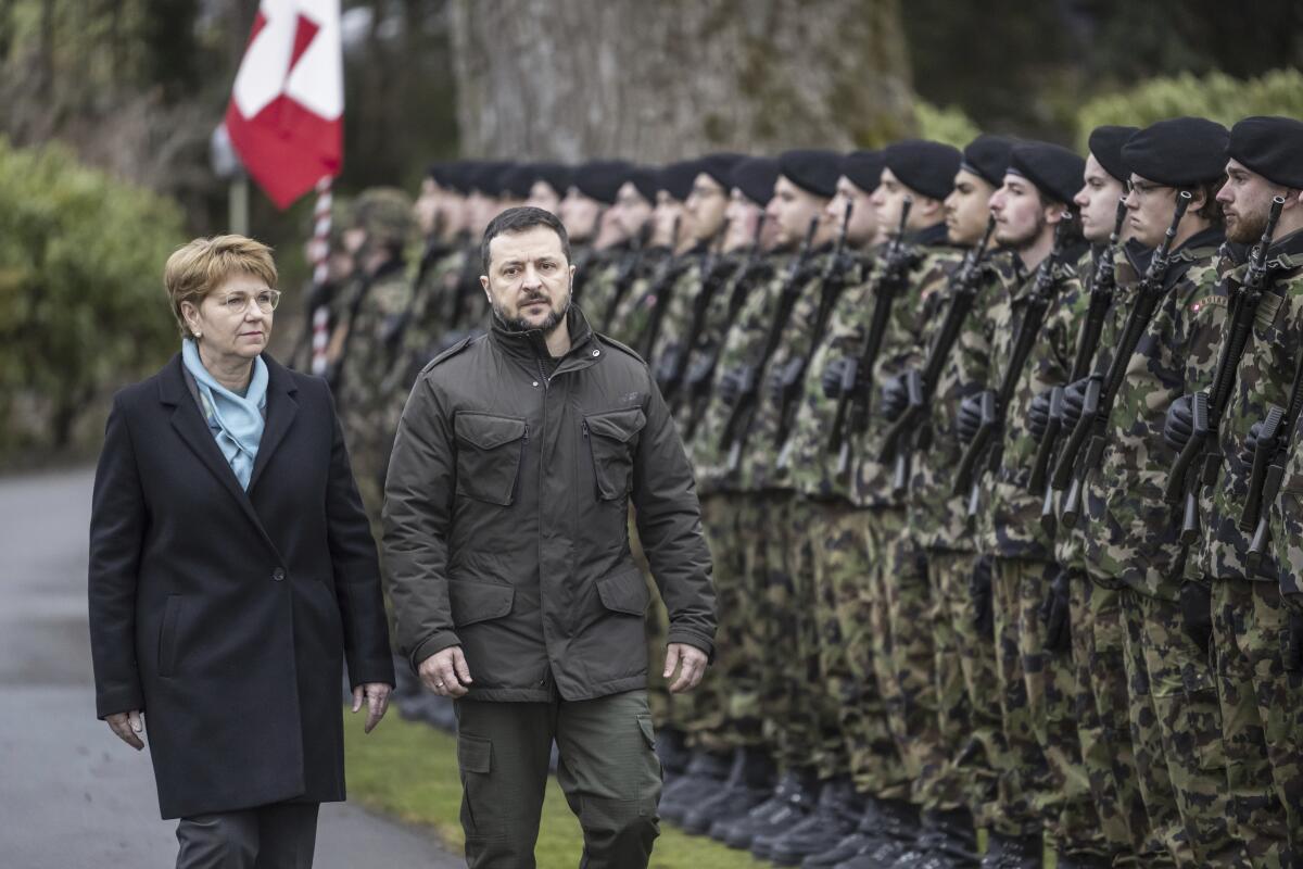 Swiss President Viola Amherd and Ukrainian President Volodymyr Zelensky pass an honor guard  