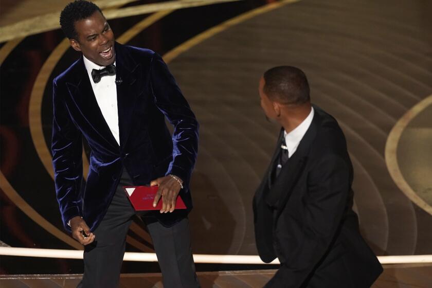 El presentador Chris Rock, izquierda, reacciona tras ser golpeado en el escenario por Will Smith al presentar el premio a mejor documental en los Oscar el domingo 27 de marzo de 2022, en el Teatro Dolby en Los Angeles. (Foto AP/Chris Pizzello)
