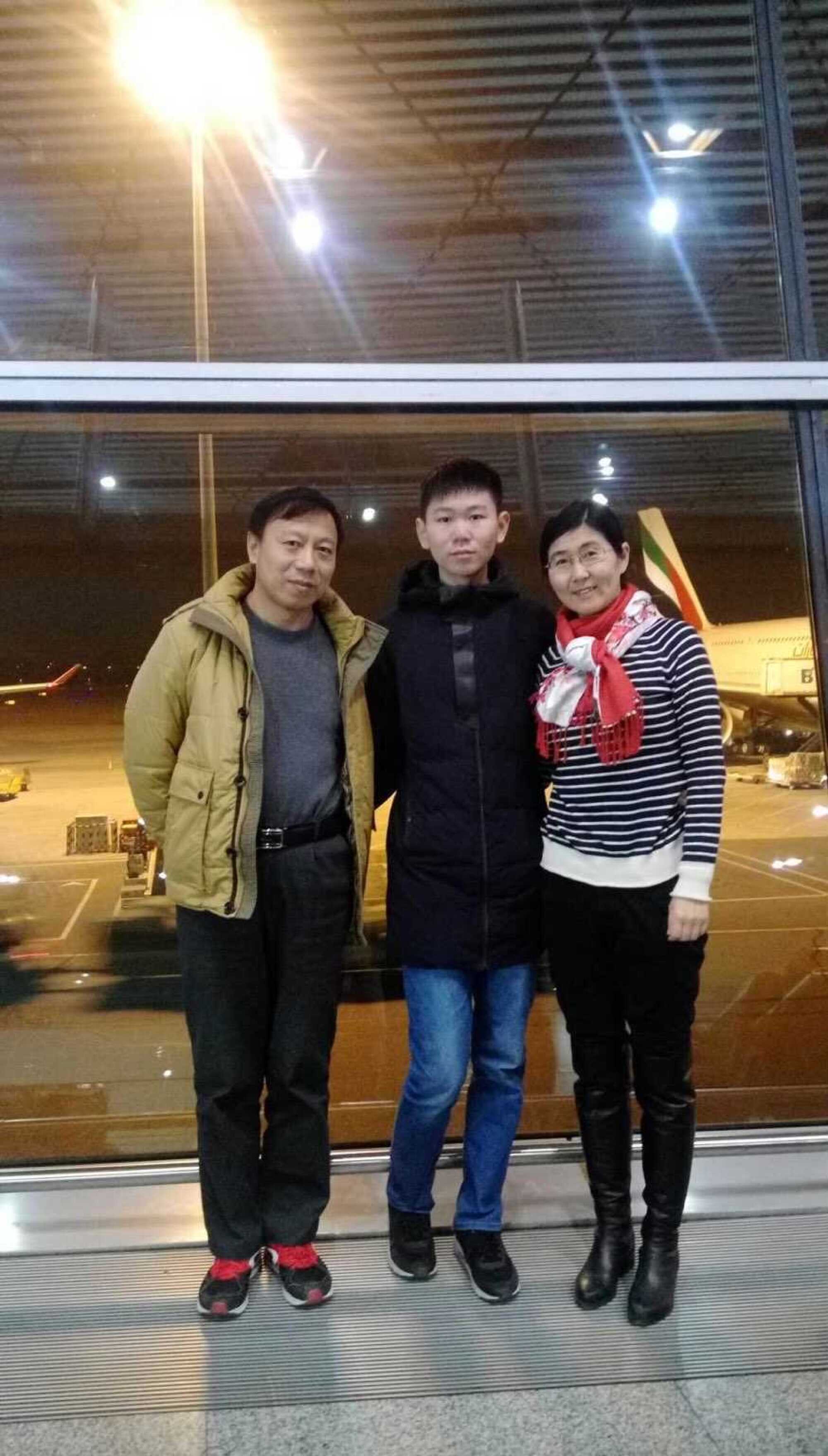 A young man is flanked by his father, left, and mother