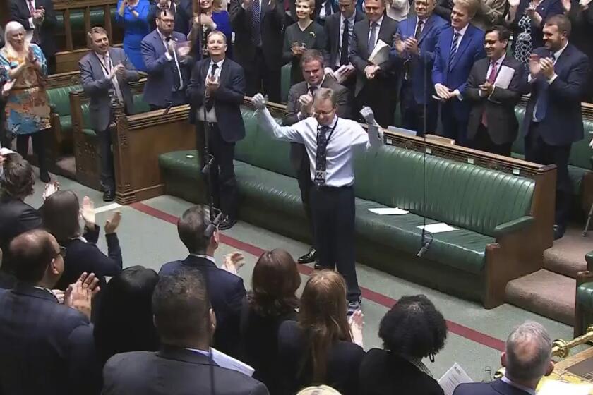 Craig Mackinlay, Conservative MP for South Thanet, is applauded by members of parliament as he returns to the House of Commons for the first time since he was rushed into hospital with sepsis on September 28, which left him with both of his hands and feet amputated, at the Parliament in London, Wednesday May 22, 2024. (House of Commons/UK Parliament via AP)
