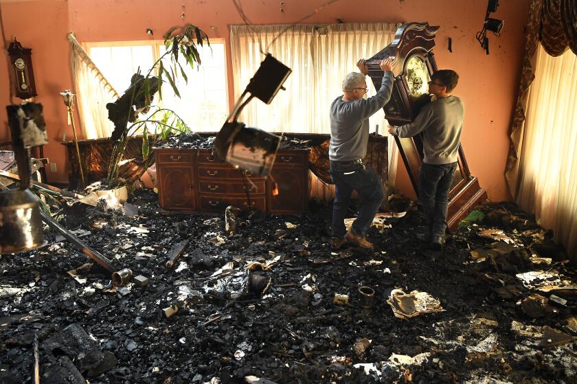 PORTER RANCH, CALIFORNIA OCTOBER 11, 2019-Jesse Stancaronere receives help from his grandson Jesse Lasher as they move a grandfather clock that received no damage after the Saddleridge Fire burned along Beaufait Ave. in Porter Ranch Friday. The clock has been through three fires and one earthquake according to Stancarone. (Wally Skalij/Los Angeles Times)