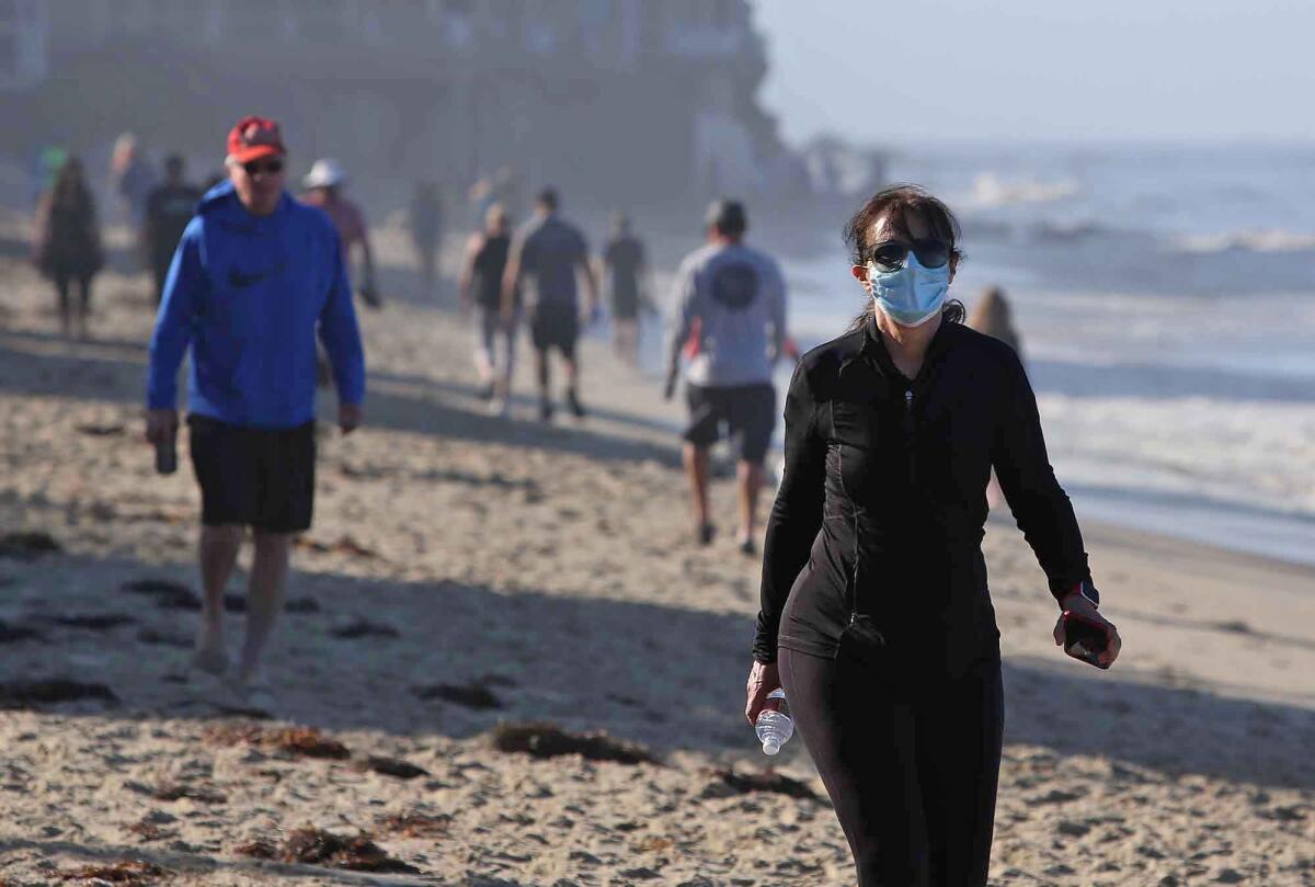People walk the sands in Laguna Beach on Tuesday.