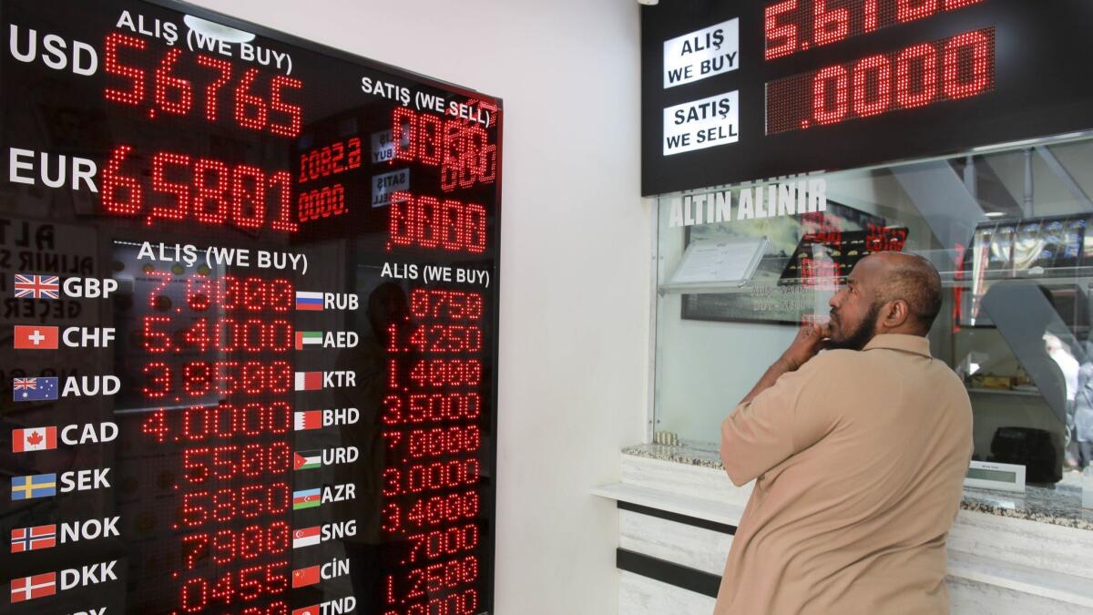 A man checks foreign currency exchange rates in Istanbul after financial shockwaves ripped through Turkey on Friday after its currency nose-dived on concerns about its economic policies and a dispute with President Trump