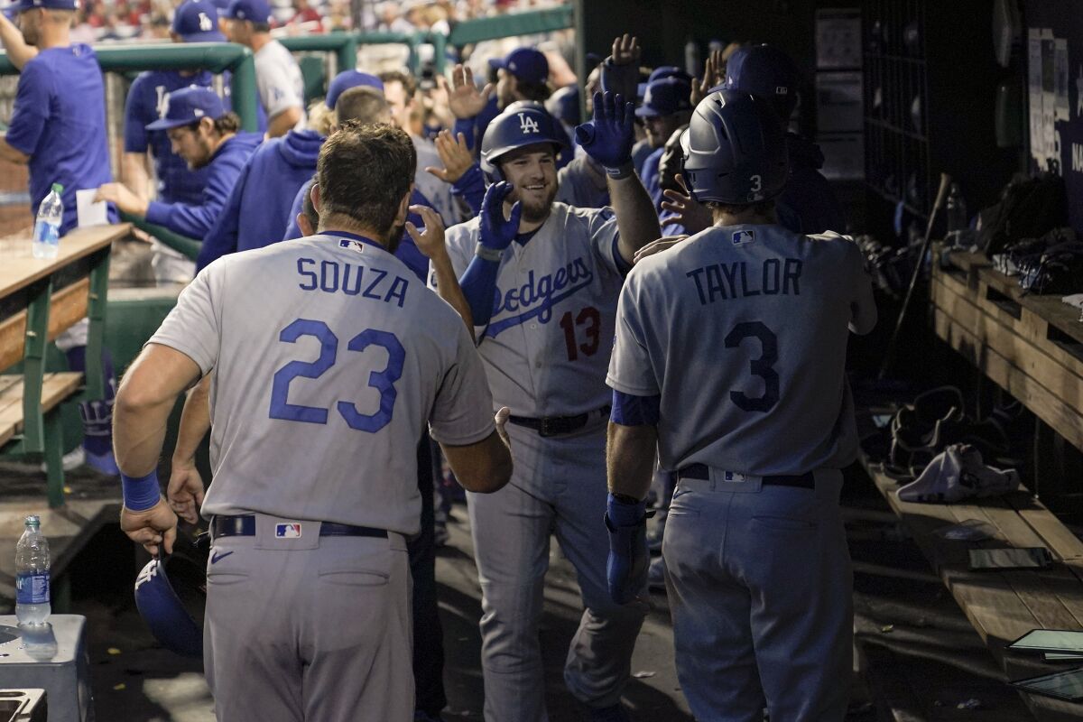 Max Muncy, center, is greeted in the dugout by teammates after hitting a grand slam in the fifth inning.
