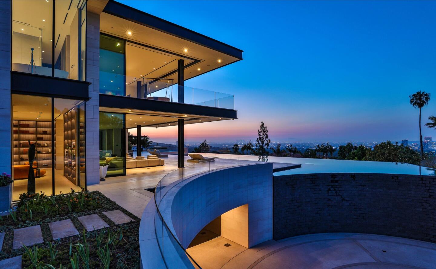 The side of the home looking into the glass-walled rooms and at the sky and trees.