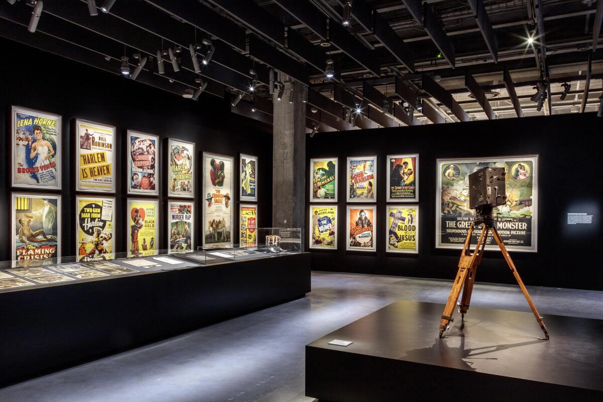 An installation view of a gallery shows a vintage camera and walls lined with film posters.