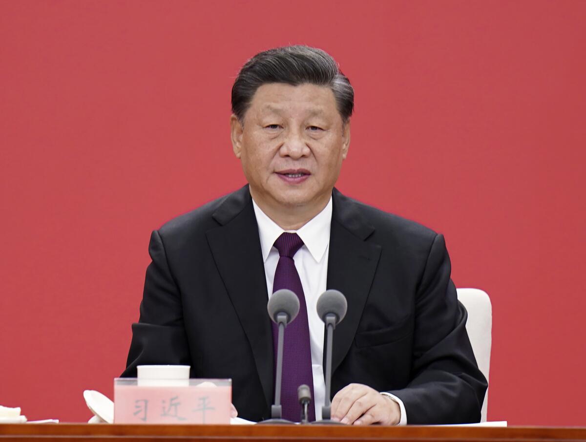 A man in a suit and tie sits in front of two microphones.