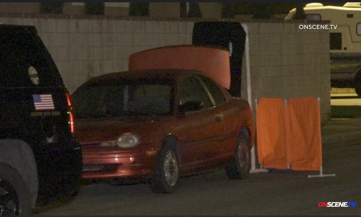 A four-door sedan with the trunk open is seen in dim light.