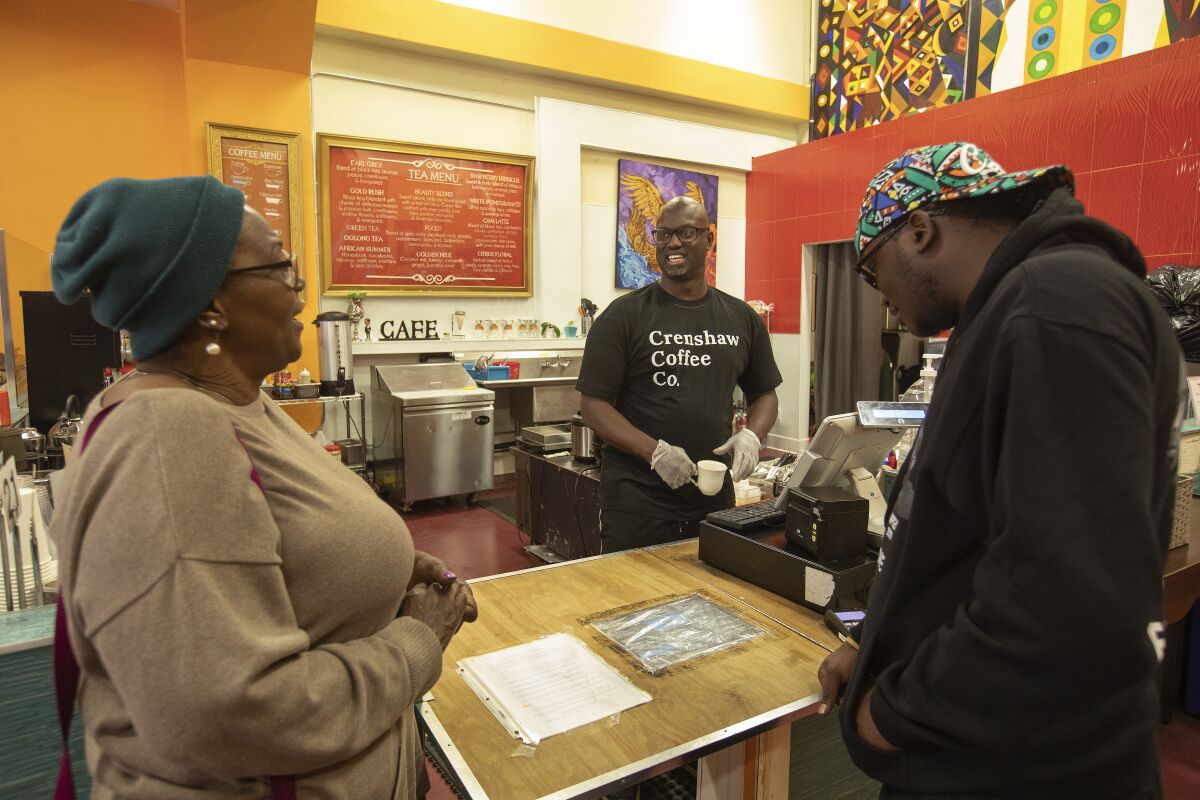 Tony Jolly, center, owner of Hot and Cool Cafe in South Los Angeles, talks to customers Frinzetta Henry, left, and Frank Bisase as they make up their minds for a take out order.
