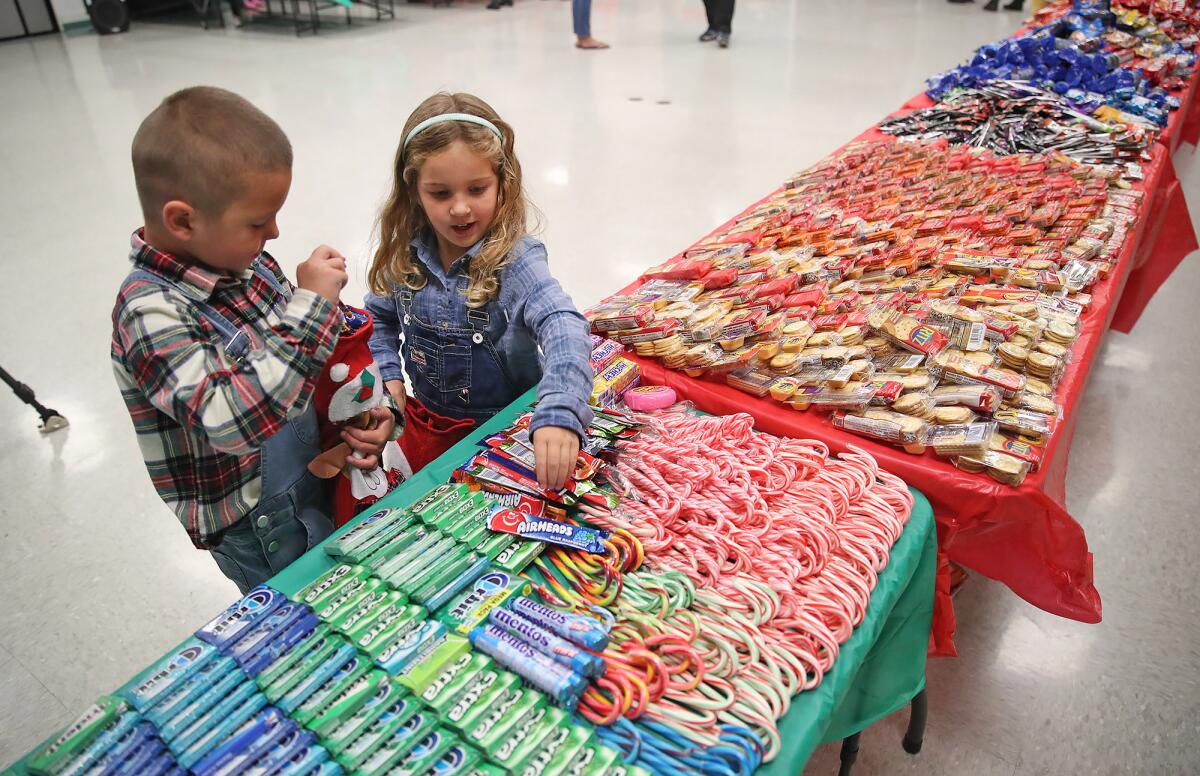 Calvin Schmidt, 4 1/2, and Maren Lee, help fill stockings during Thursday night's event.