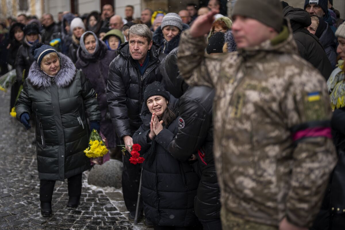 Women walk by the "Memory wall of fallen defenders in Kyiv, Ukraine, Tuesday, Feb. 7.