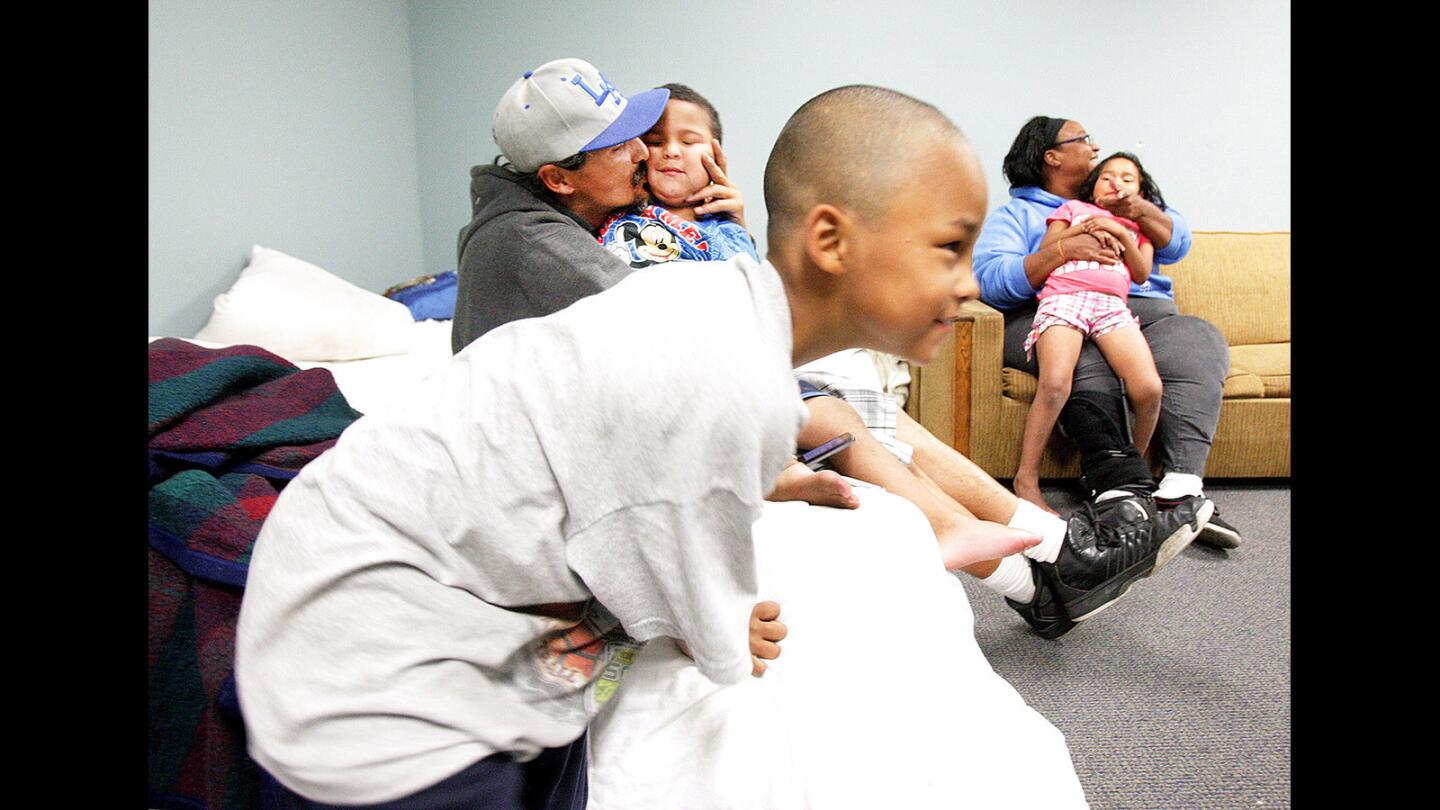Andres Camacho, 6, runs to the other side of the room with his parents Gilbert Camacho and Kerlissa Lefeged holding his younger brother Amellio, 4, and sister Olyvia, 6, in the room they are staying in at Glendale Presbyterian Church as part of Family Promise of the Verdugos on Wednesday, November 4, 2015 where they have stayed for the week. Family Promise of the Verdugos is a group of 11 local churches that have opened their doors for homeless families, rotating week-by-week, providing shelter and food. (Tim Berger/Staff Photographer)