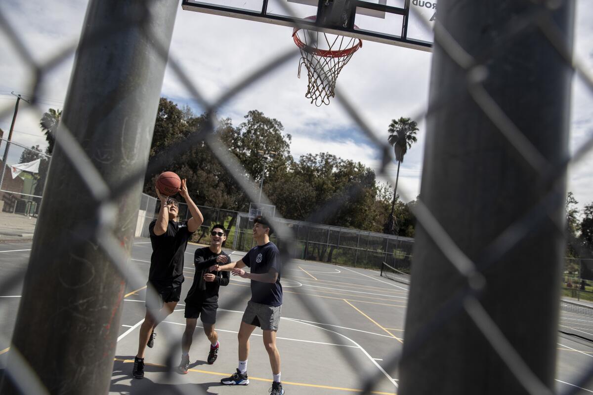 Timothy Chu, left, Michael Hashimoto and Kevin Liu on a basketball court at Hazard Park in L.A.