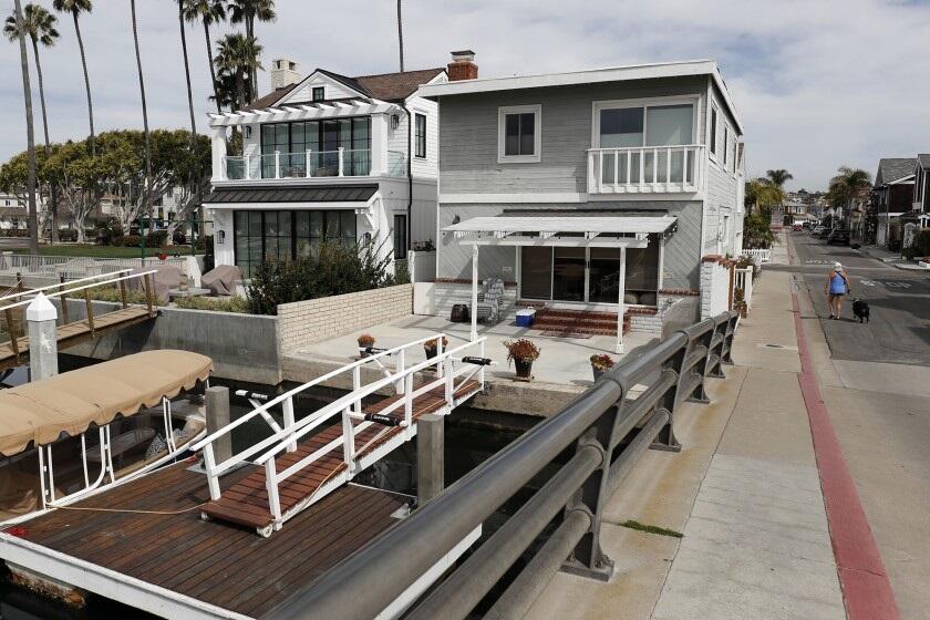 A woman walks her dog past a waterfront duplex on 38th Street on Newport Island. The duplex is used as a vacation rental.