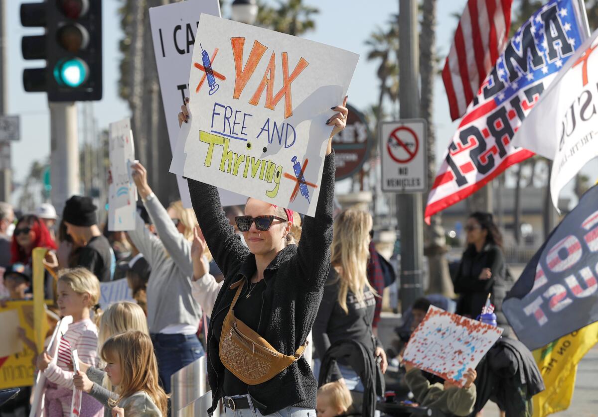 A supporter holds a sign in support of Children's Medical Freedom rally at the Huntington Beach Pier Plaza on Monday.