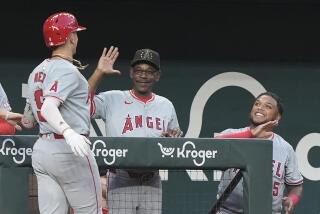 The Angels' Zach Neto is congratulated in the dugout by manager Ron Washington and teammate Willie Calhoun
