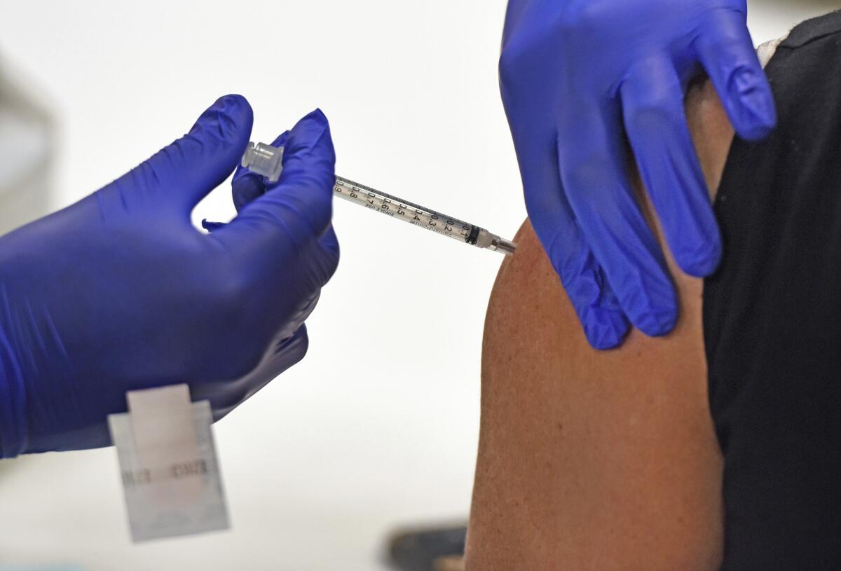 Gloved hands administer a shot in a patient's arm