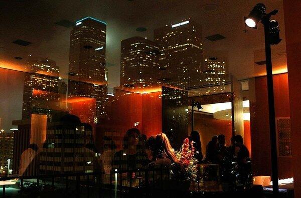 The downtown Los Angeles skyline is reflected in windows on the sixth floor of the Los Angeles Times Building as guests attend Bite Nite, a night with Jonathan Gold celebrating his 101 best L.A. restaurants.