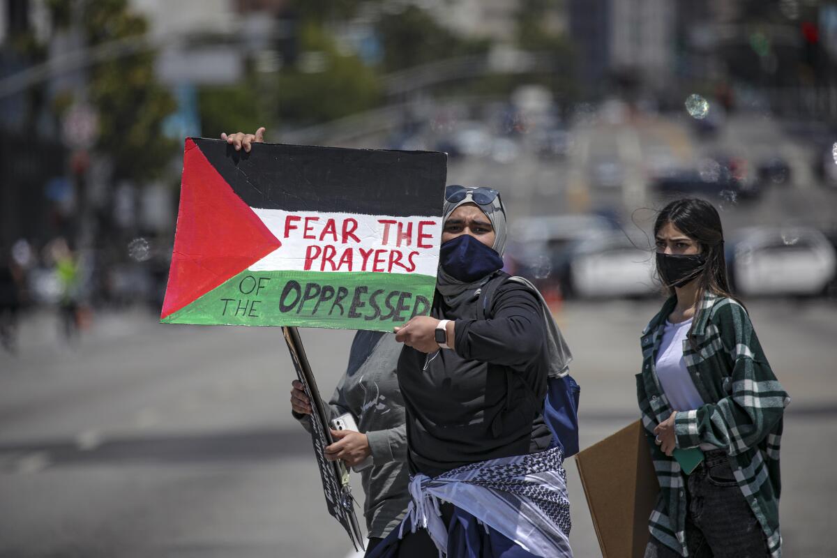 A protester holds a sign that says "Fear the prayers of the oppressed."