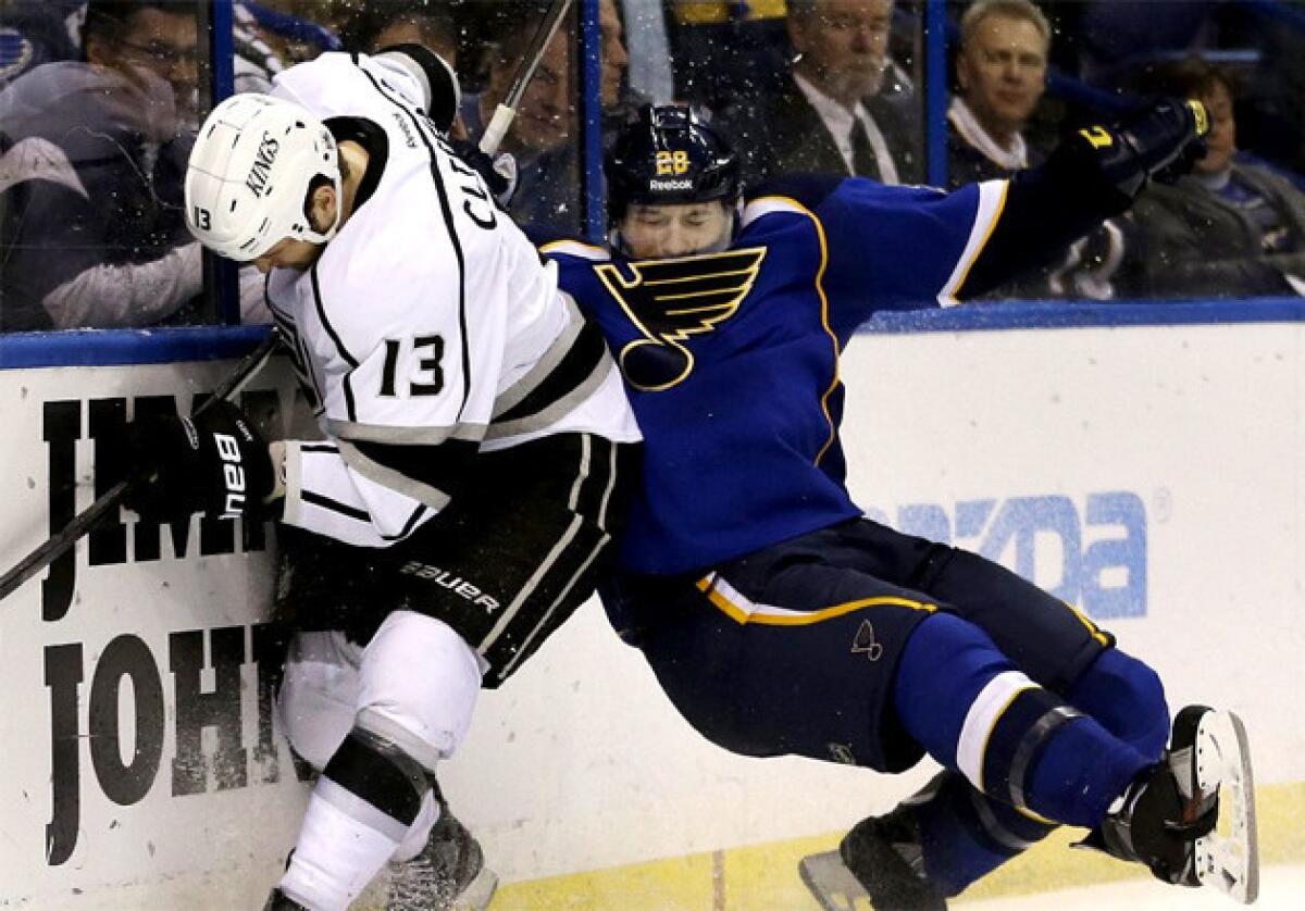 The Kings' Kyle Clifford, left, slams the St. Louis Blues' Ian Cole against the boards as they battle for a loose puck back in February.