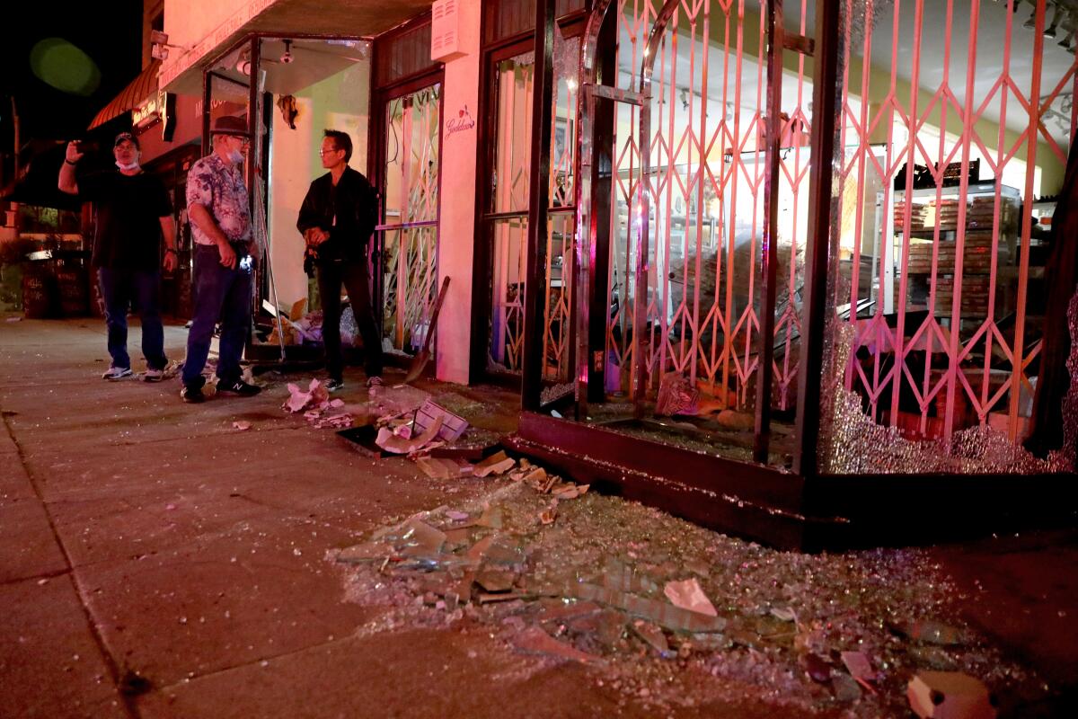 Shop owners assess the damage after looters and vandals ransack businesses along Melrose Avenue on Saturday.