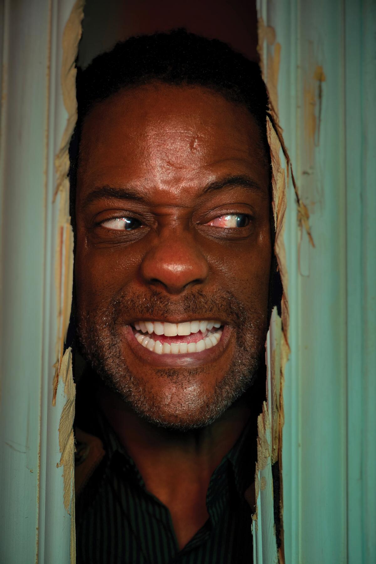 A man snarls as he peers through a hole in a door.