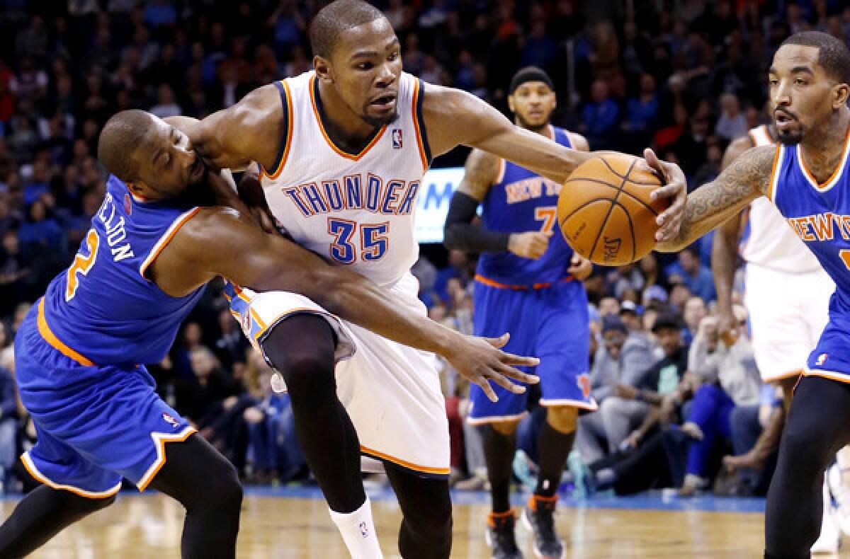 Thunder forward Kevin Durant (35) is fouled by Knicks guard Raymond Felton (2) as he drives between Felton and guard J.R. Smith in the fourth quarter of a game on Sunday in Oklahoma City.