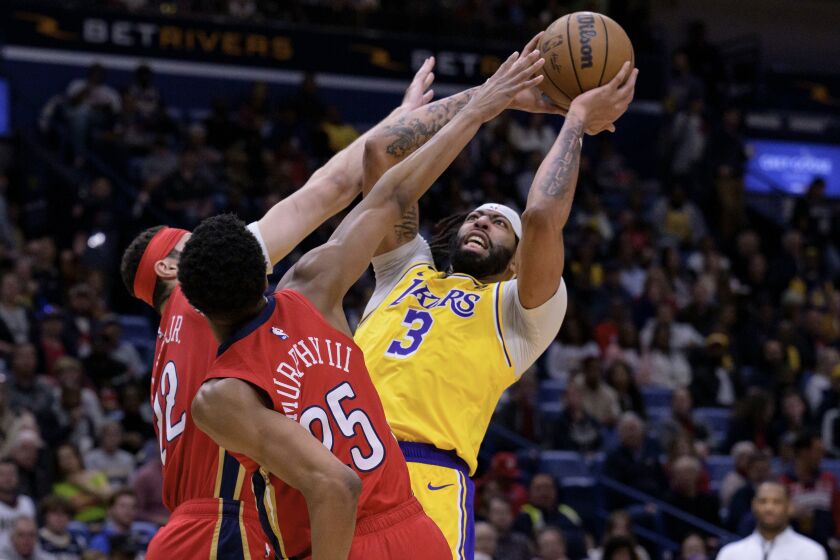 Los Angeles Lakers forward Anthony Davis (3) shoots against the double team of New Orleans Pelicans forward Larry Nance Jr. (22) and guard Trey Murphy III (25) in the first half of an NBA basketball game in New Orleans, Tuesday, March 14, 2023. (AP Photo/Matthew Hinton)