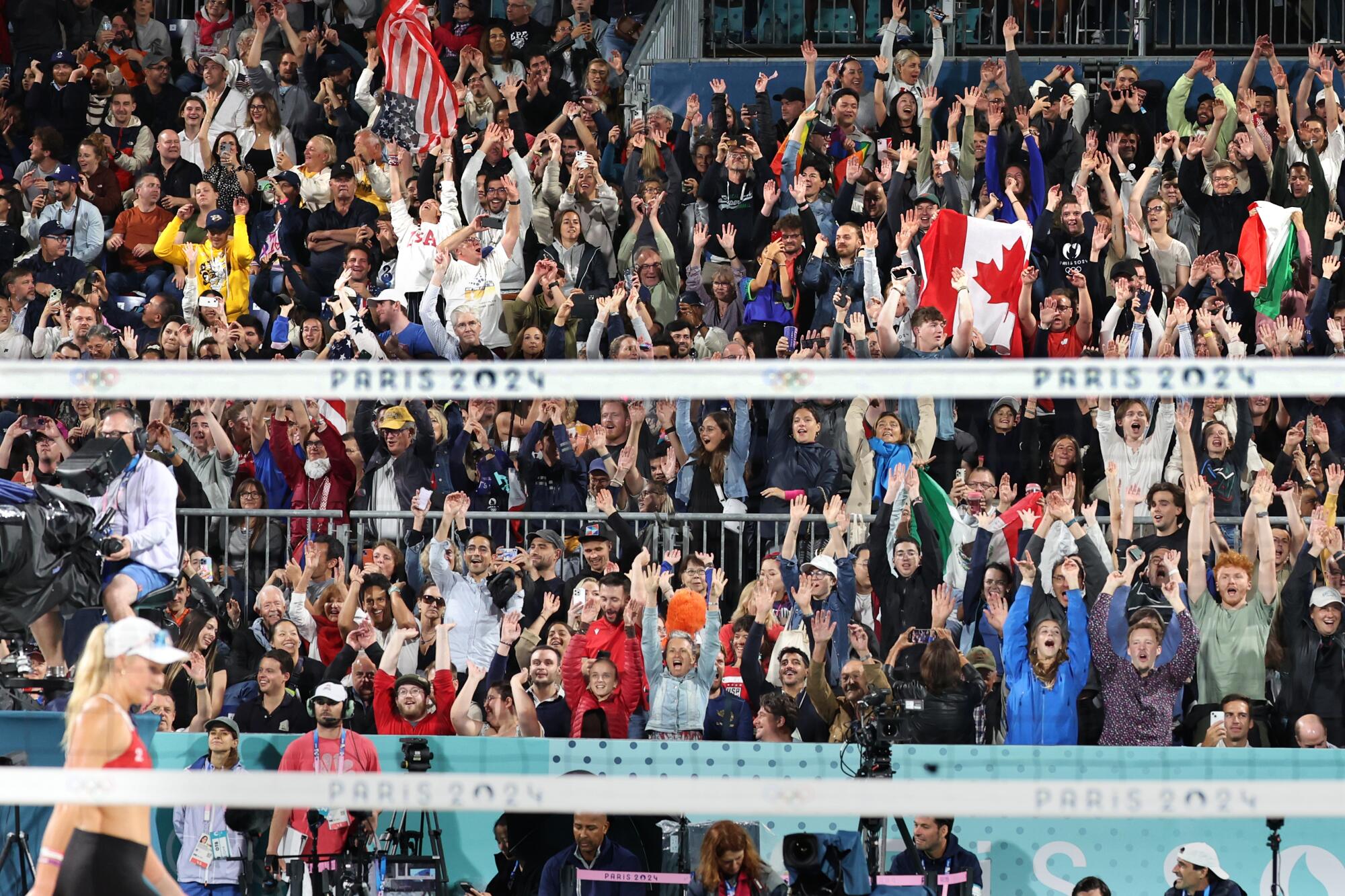 Fans do the wave during a beach volleyball match between the U.S. and Canada at the Paris Olympics.