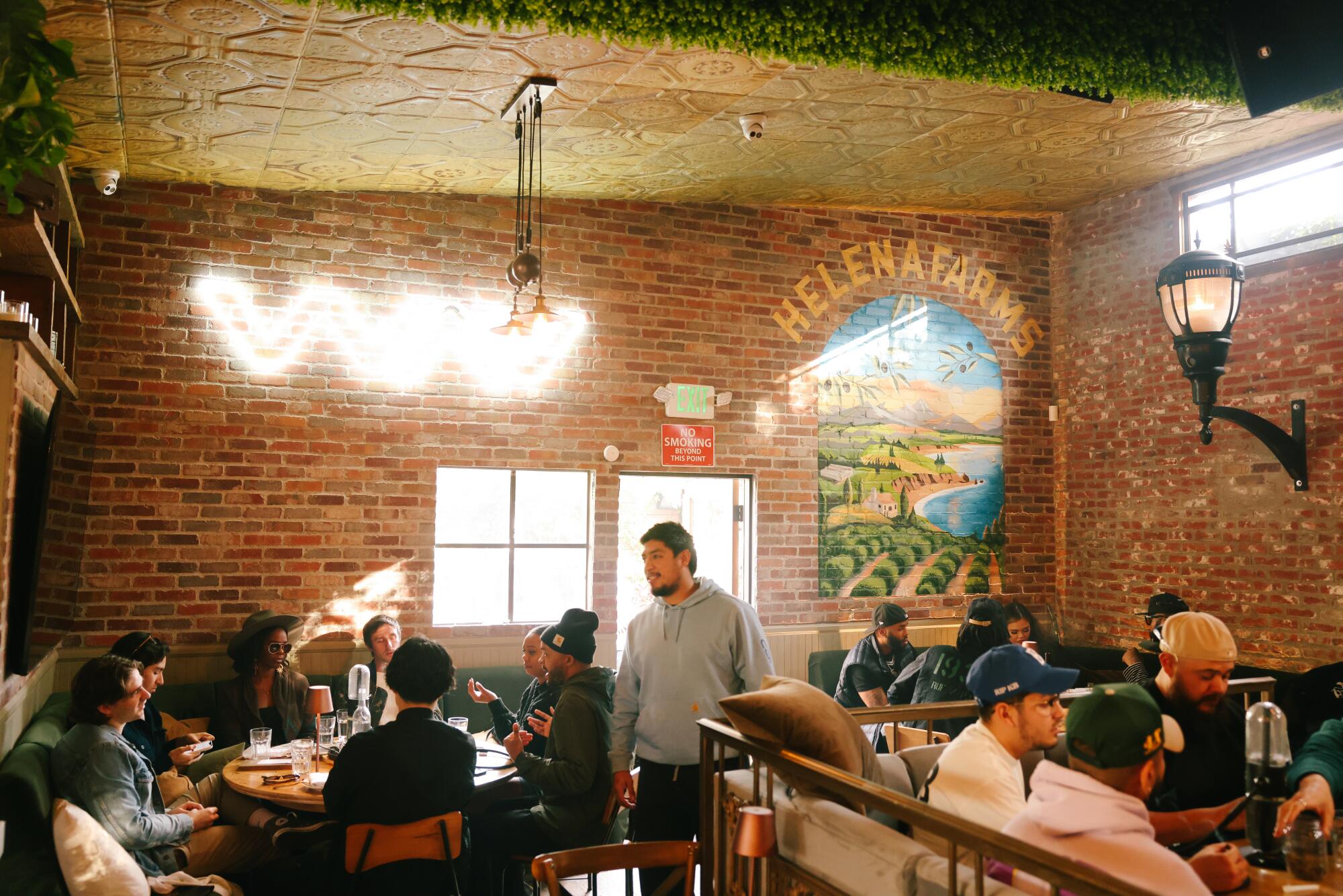 People sitting in a restaurant-like space with brick walls and cannabis-brand art.