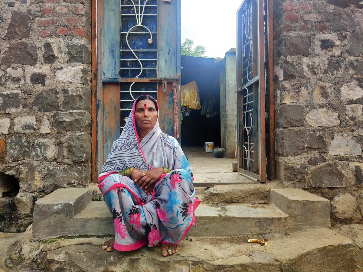 A woman sits on steps in front of a house.