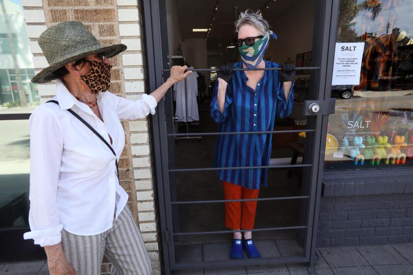 VENICE, CA - MAY 07, 2020 - - Salt women's clothing store owner Holly Boies, 53, right, talks with longtime shopper Enid Koffler at the front door of her store on Abbott Kinney Blvd. in Venice on May 7, 2020. Boies is is planning to open her store for curbside pick-up tomorrow. "We'll see how it goes. I'll be here," Boies said about opening her business for curbside pick-up. She's really struggling. She's owned the clothing store on Abbott Kinney for the past 17 years. Her landlord is cutting her some slack right now on paying rent and she's waiting for an SBA loan. She's applied for unemployment for a small business loan and but does not qualify for a PPP loan because she is the sole person who runs the store. Retail businesses, such as book stores, clothing stores, toy stores and florists, can reopen for curbside pickup starting Friday. In order to do so, they are being asked to develop contactless payment procedures, have hand sanitizer available for employees and customers, ensure employees have proper protective gear, and ask employees to deliver goods to customers' cars when possible. (Genaro Molina / Los Angeles Times)