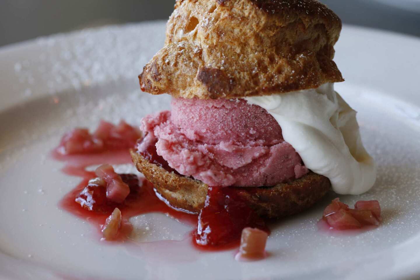 A strawberry rhubarb ice cream profiterole with strawberries and whipped cream.