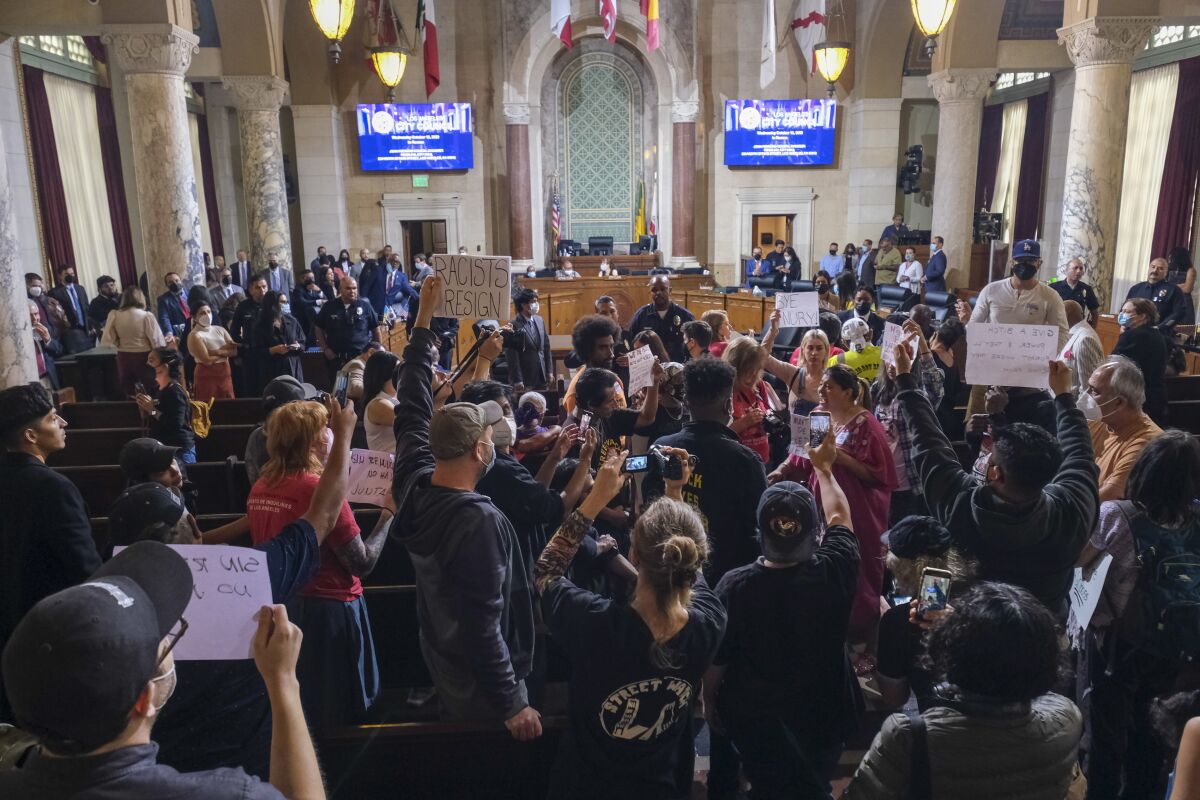 FILE - People hold signs and shout slogans before the cancellation of the Los Angeles City Council meeting on Oct. 12, 2022 in Los Angeles. According to a Tuesday, Nov. 29 statement, Los Angeles police have sought a search warrant for the Reddit website as they try to identify the person who leaked a racist discussion between City Council members and a powerful labor leader, causing a scandal that has rocked the community and shaken faith in its lawmakers. (AP Photo/Ringo H.W. Chiu, File)