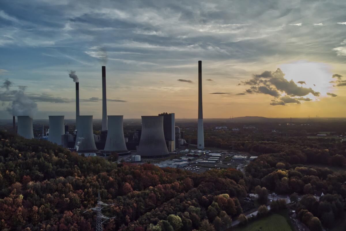 The sun sets behind a power plant.