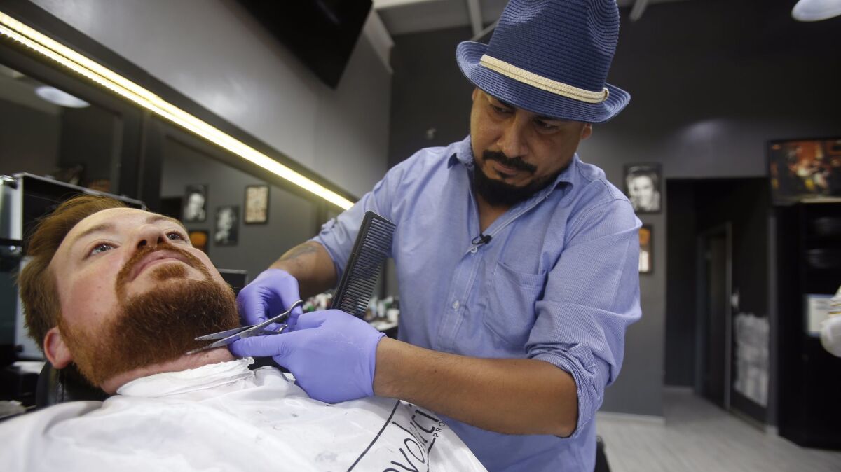 Barber Miguel "Robo" Angel Gomez Davalos trimming reporter Phillip Molnar's beard at Cali Cuts Barber Shop in Colonia Cacho.