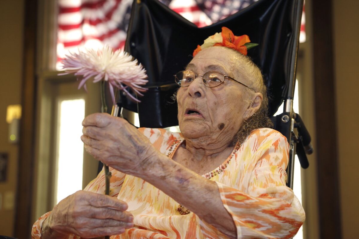 On July 3, 2014, Gertrude Weaver holds a flower given to her a day before her 116th birthday in Camden, Ark.