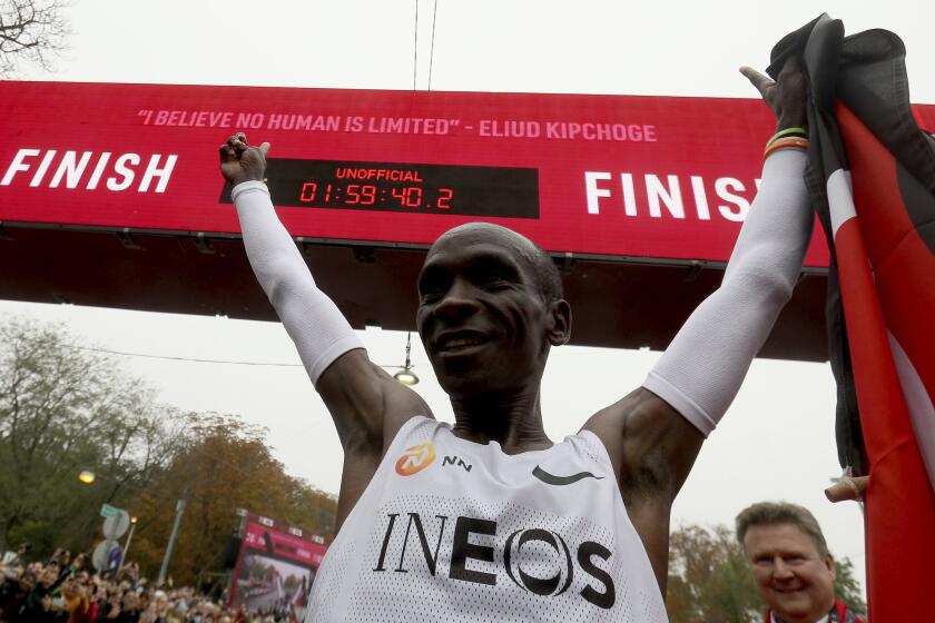 Marathon runner Eliud Kipchoge from Kenya celebrates under the clock after crossing the finish line of the INEOS 1:59 Challenge after 1:59:40 in Vienna, Austria, Saturday, Oct. 12, 2019. He is the first human ever to run a marathon under two hours. (AP Photo/Ronald Zak)